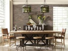 
                    
                        Exposed brick and enormous windows provide an urban backdrop for this dining room. A mix of seating around a long, wood dining table creates a casual atmosphere. Overhead, pendants made from repurposed wine bottles enliven the room both day and night.
                    
                