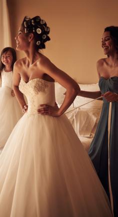Bride getting dressed for the wedding with bridesmaid and flower girl