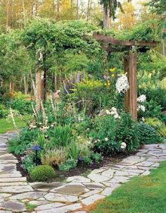 Roses and clematis climb a pergola under which peonies, lilies, and yellow foxtail lilies bloom.