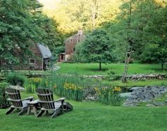 A natural pond and low-rising, mortarless stone walls adorn this backyard garden.