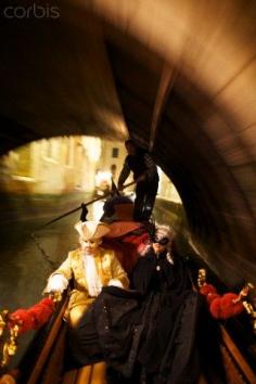 A couple in Carnival costumes ride gondola under bridge. Venice  Italy