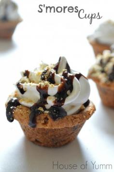 S'mores Cups.  Chocolate chip cookie cups topped with chocolate, the fluffiest Marshmallow frosting EVER and graham cracker crumbs!  YUM!! #smoresweek