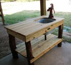 Outdoor kitchen table with sink fed by a garden hose.