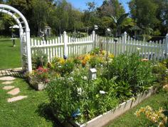 Surrounding a pond in this Garden Designer magazine reader garden is an assortment of fruit trees, flowers, and plants that are quenched with nutrient-rich water from the pond itself. #gardendesign #gardeninspiration #raisedbedgardening