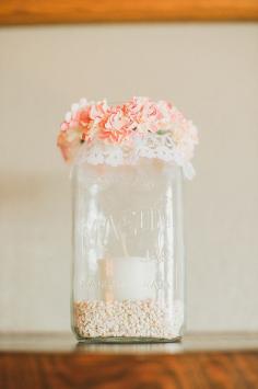 
                    
                        Romantic Garden Wedding Idea: Square mason jar lined with white rocks and a candle. Top it off with a wreath of flowers.
                    
                