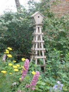 
                    
                        wooden obelisk with a birdhouse on top
                    
                
