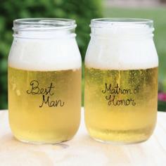 These bridal party beverage glasses make great gifts for all the friends and family standing with you on your big day. The 16 ounce glass mason jars are imprinted in black with the bridal party position and then you can optionally add two lines of custom engraved text to the back on the jar. Features Glass beverage jars with black wording "Matron of Honor" and "Best Man". Size - 5 1/8 in. tall 3 1/8 in. diameter. Holds 16 ounces. Set of two.